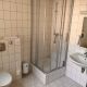 gefliestes Badezimmer mit Dusche, Waschbecken, Spiegel und WC