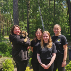 4 Frauen und ein Hund schauen in die Kamera und lächeln