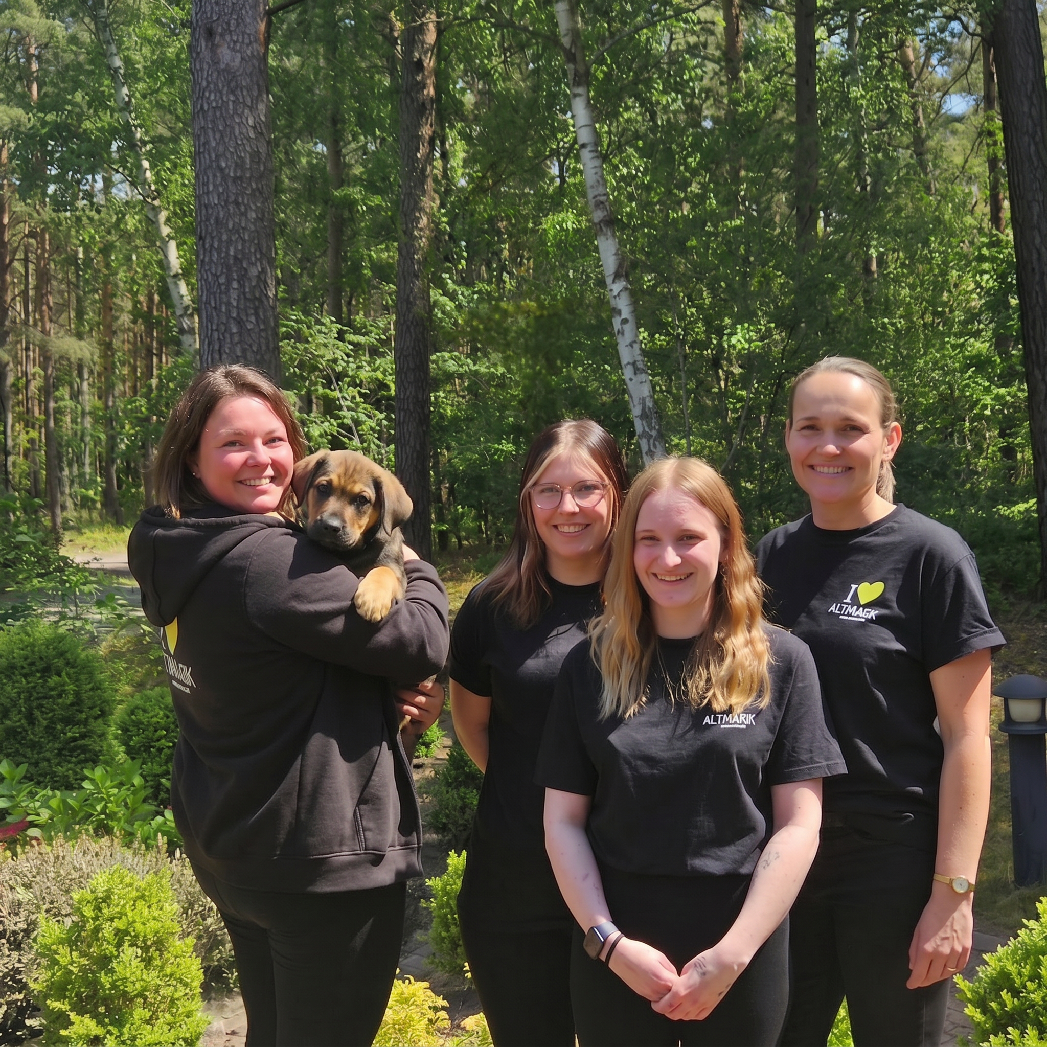 4 Frauen und ein Hund schauen in die Kamera und lächeln